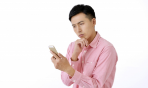 携帯を見て考え込む男