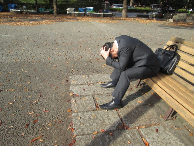 ベンチで絶望に打ちひしがれる男